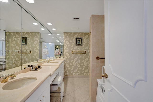 bathroom featuring tile patterned flooring, a tile shower, and vanity