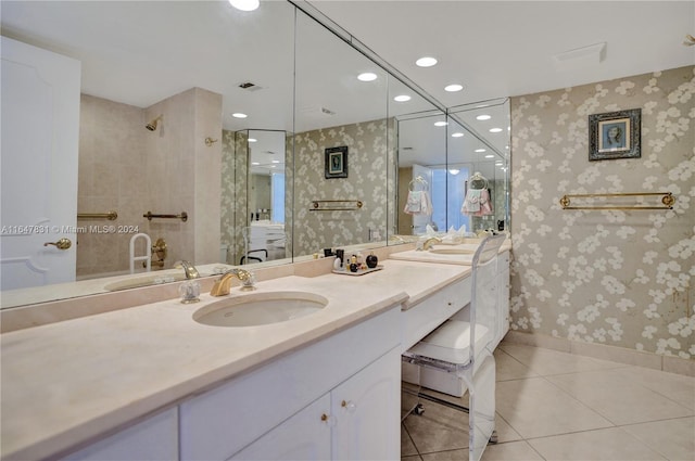 bathroom featuring tile patterned flooring, a tile shower, and vanity