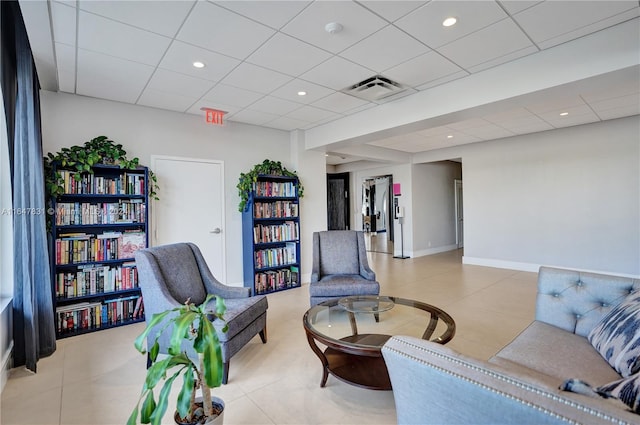 interior space with a paneled ceiling and light tile patterned flooring