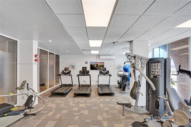 workout area with a drop ceiling, carpet, and an AC wall unit