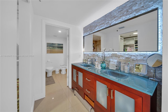 bathroom featuring toilet, tile patterned flooring, a bidet, tasteful backsplash, and vanity