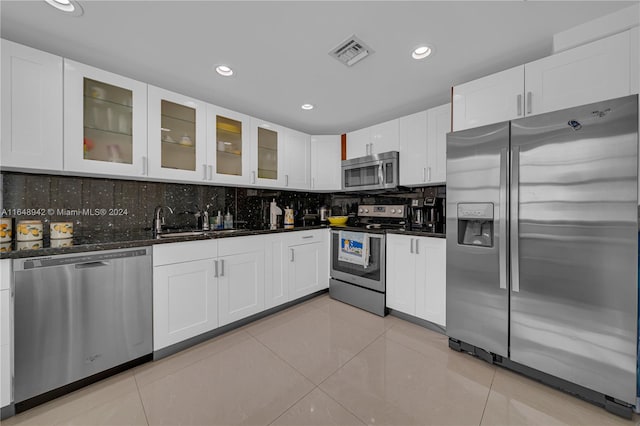 kitchen featuring light tile patterned floors, stainless steel appliances, sink, decorative backsplash, and white cabinetry