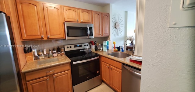 kitchen with backsplash, sink, appliances with stainless steel finishes, and light tile patterned flooring