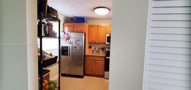 kitchen with light tile patterned floors, appliances with stainless steel finishes, and tasteful backsplash