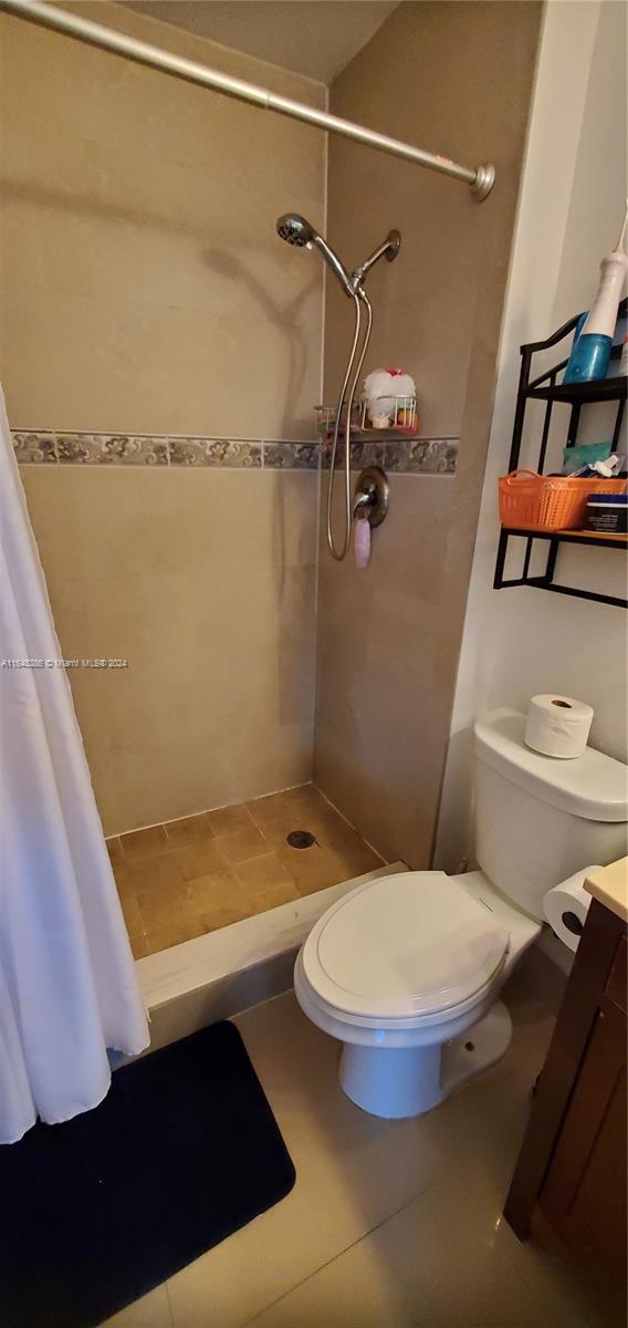 bathroom with tile patterned flooring, a shower with curtain, toilet, and vanity