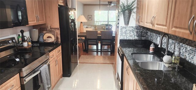 kitchen featuring black appliances, dark stone countertops, and sink