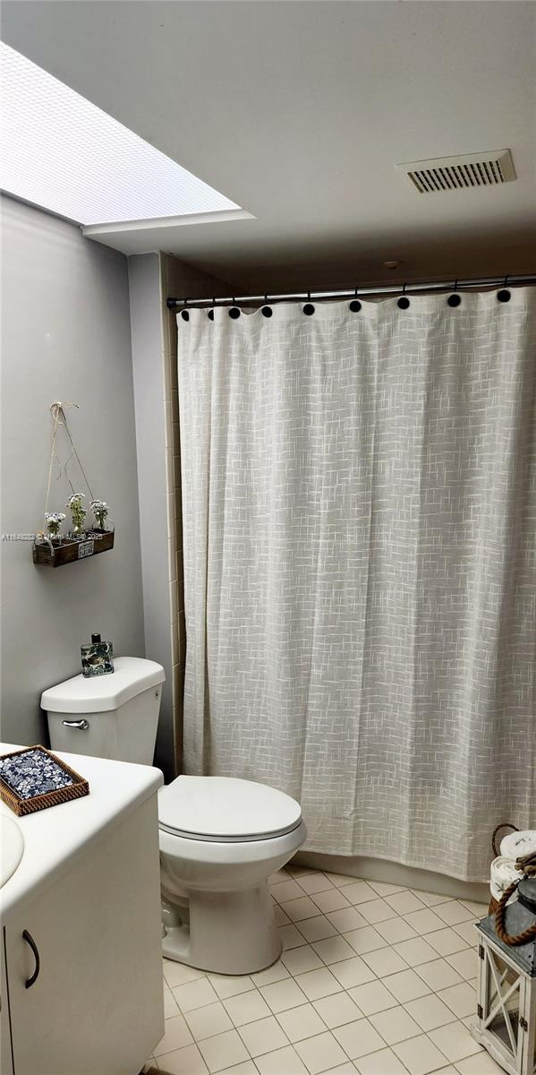 bathroom featuring toilet, a shower with curtain, and tile patterned flooring