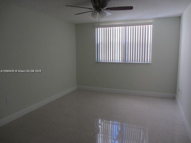 unfurnished room with ceiling fan, a wealth of natural light, and tile patterned flooring