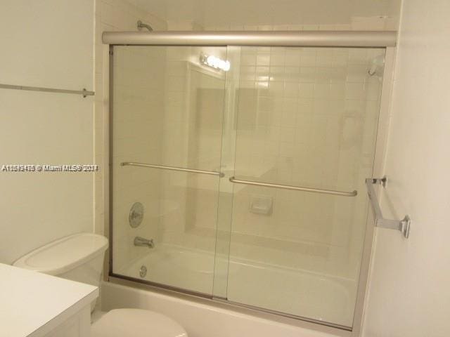 full bath with toilet, bath / shower combo with glass door, and vanity