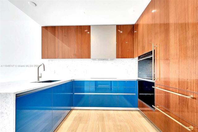 kitchen with sink, black oven, stovetop, light wood-type flooring, and decorative backsplash