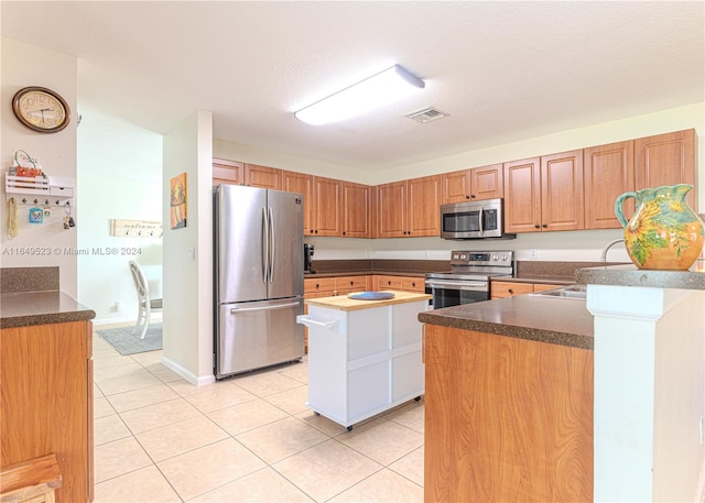 kitchen with a textured ceiling, light tile patterned floors, stainless steel appliances, kitchen peninsula, and sink