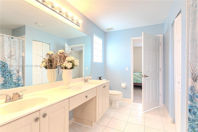 bathroom with a textured ceiling, vanity, toilet, and tile patterned flooring