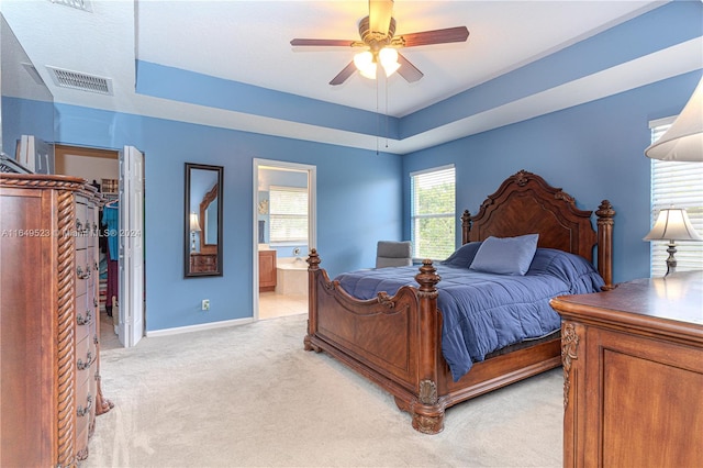 bedroom featuring light colored carpet, connected bathroom, ceiling fan, and a closet