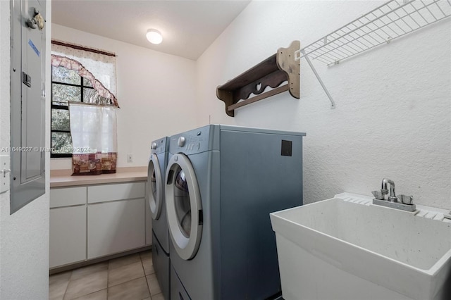 washroom with light tile patterned floors, washer and dryer, and sink