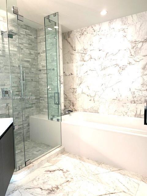 851 NE 1st Ave Unit 2110, Miami, FL 33132 - bathroom featuring a bath, vanity, a stall shower, tile walls, and marble finish floors