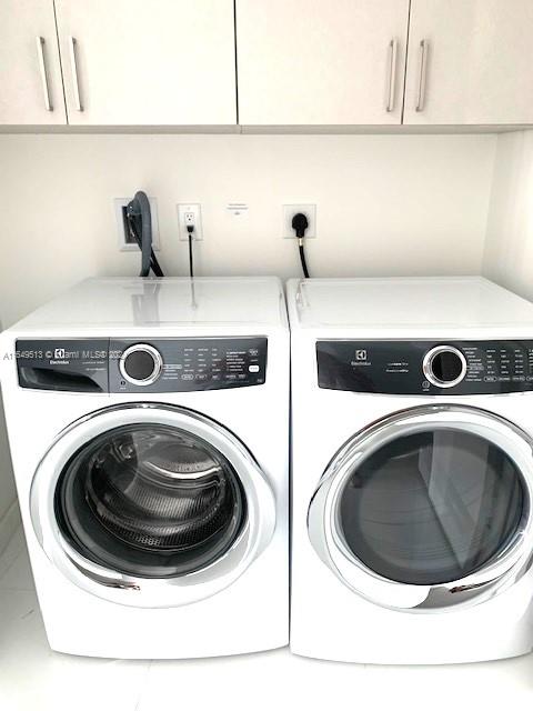 washroom featuring washing machine and dryer and cabinets