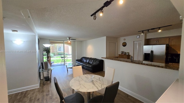 dining space with a textured ceiling, ceiling fan, dark hardwood / wood-style floors, and track lighting