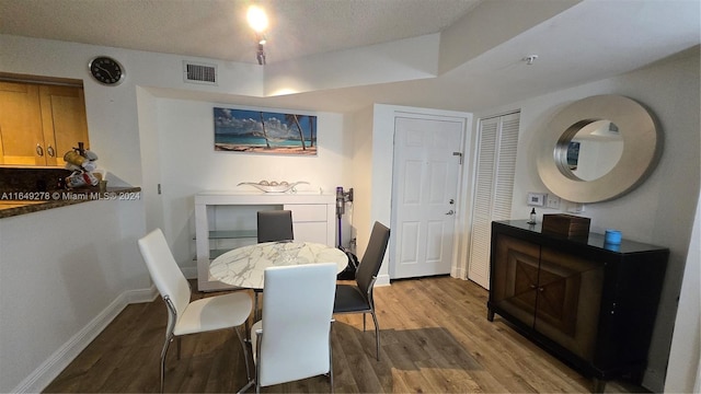 dining room featuring a textured ceiling and wood-type flooring