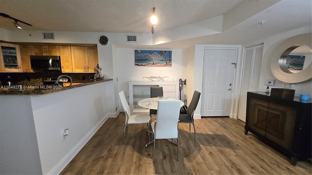 dining area featuring track lighting, hardwood / wood-style floors, and a textured ceiling