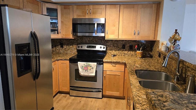 kitchen featuring sink, stone countertops, light hardwood / wood-style flooring, stainless steel appliances, and decorative backsplash