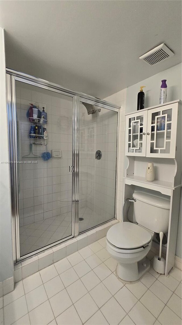 bathroom featuring walk in shower, tile patterned floors, and toilet