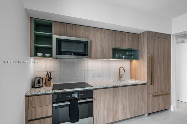 601 NE 1st Ave Unit 3101, Miami, FL 33132 - kitchen with backsplash, a sink, open shelves, light stone countertops, and black appliances