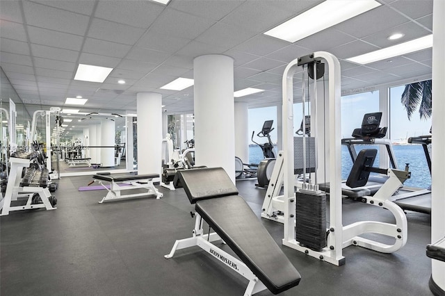 gym featuring a water view and a paneled ceiling