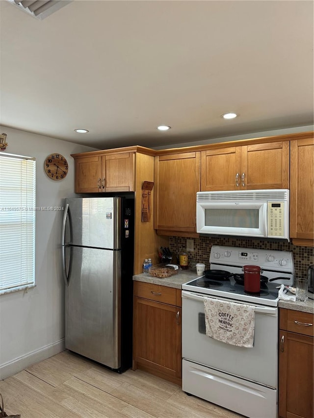 kitchen featuring white appliances, backsplash, and light wood-type flooring