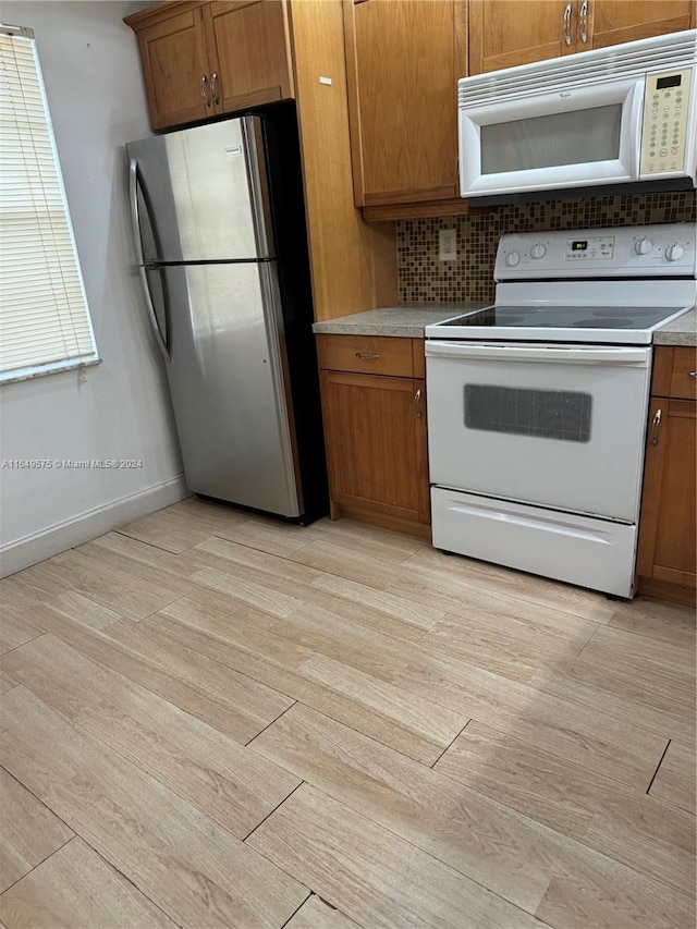 kitchen featuring white appliances, light hardwood / wood-style floors, and backsplash