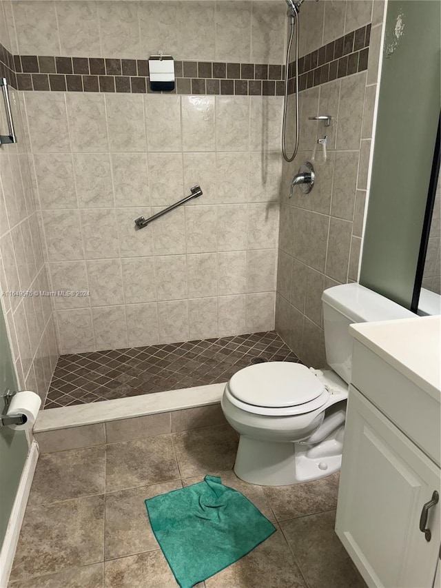 bathroom with a tile shower, tile patterned floors, vanity, and toilet