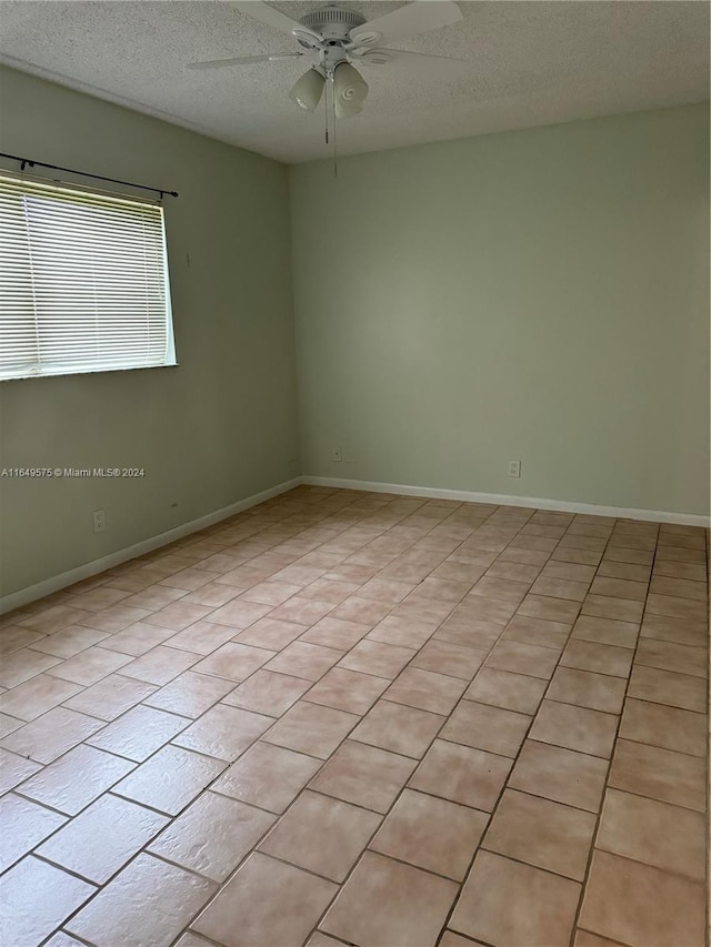 tiled spare room featuring ceiling fan and a textured ceiling