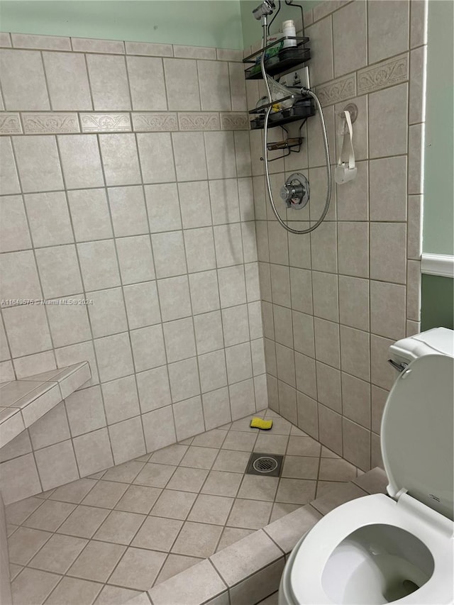 bathroom featuring tile patterned flooring, toilet, and tiled shower