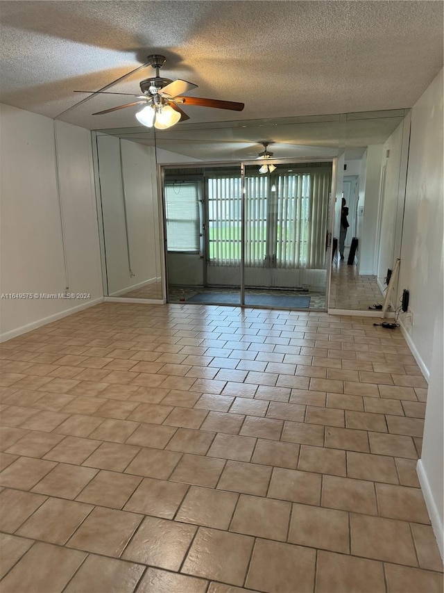 tiled empty room with ceiling fan and a textured ceiling