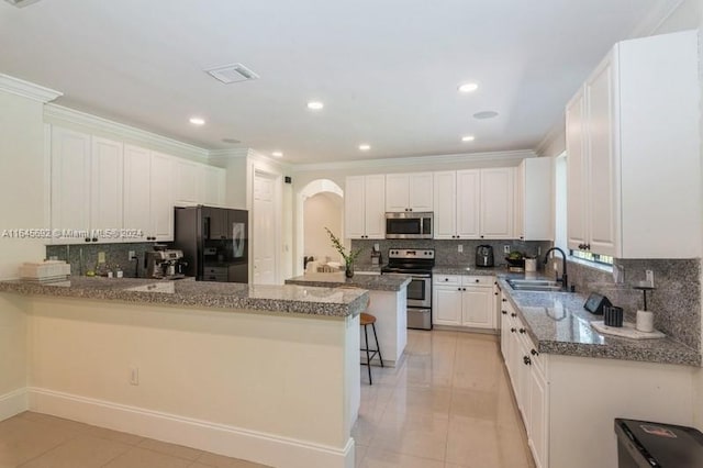 kitchen with stainless steel appliances, white cabinets, kitchen peninsula, sink, and backsplash