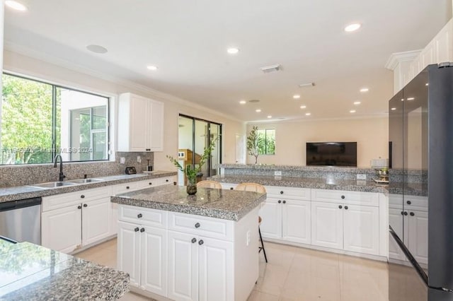 kitchen with white cabinets, a center island, high end black fridge, and sink