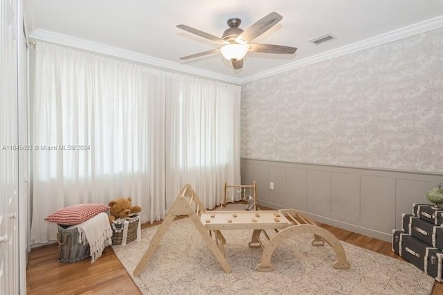 rec room with hardwood / wood-style floors, ceiling fan, and crown molding