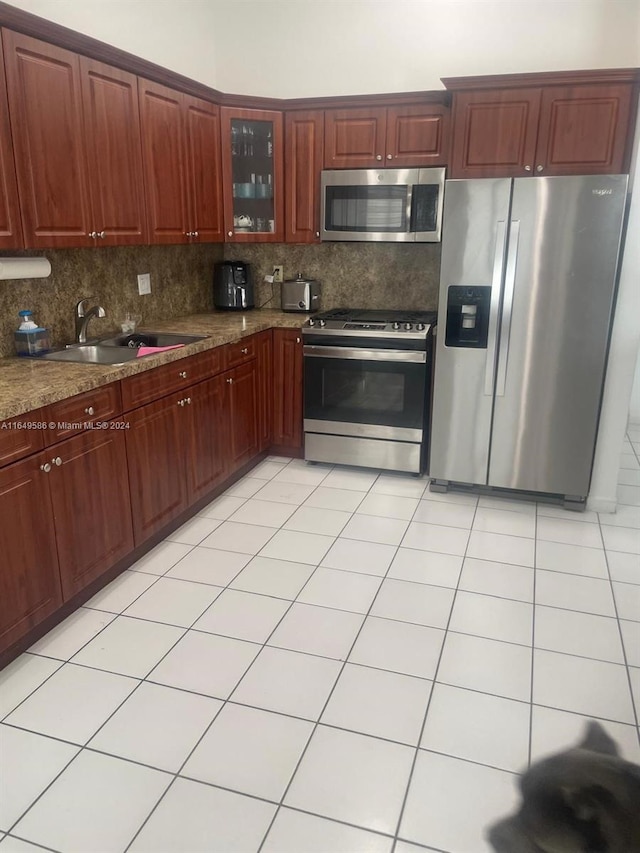 kitchen featuring light tile patterned floors, stainless steel appliances, sink, decorative backsplash, and stone counters