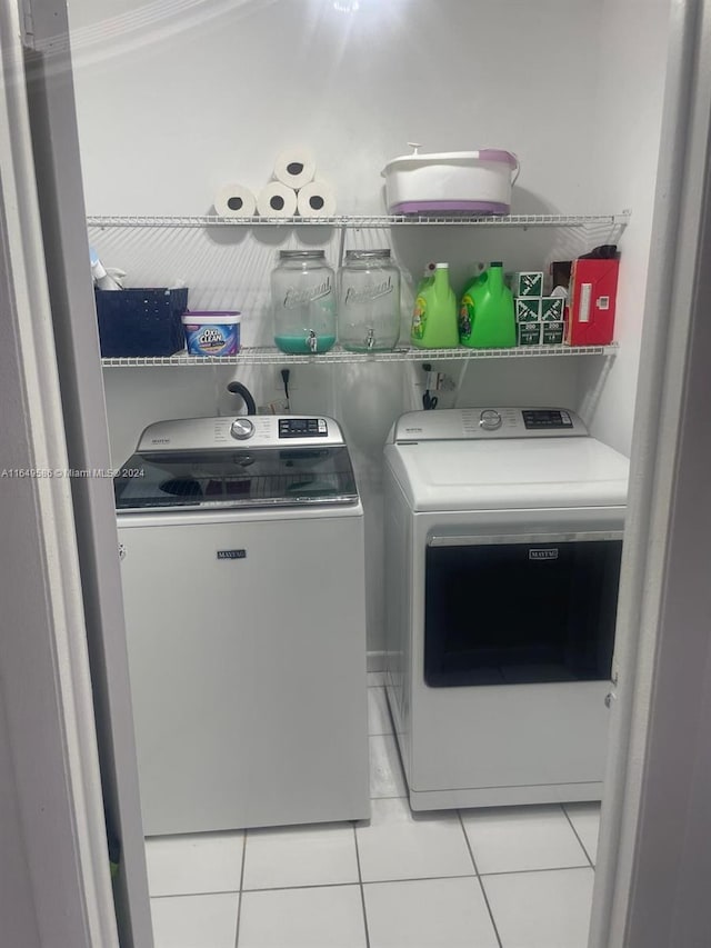 laundry area with independent washer and dryer and light tile patterned floors