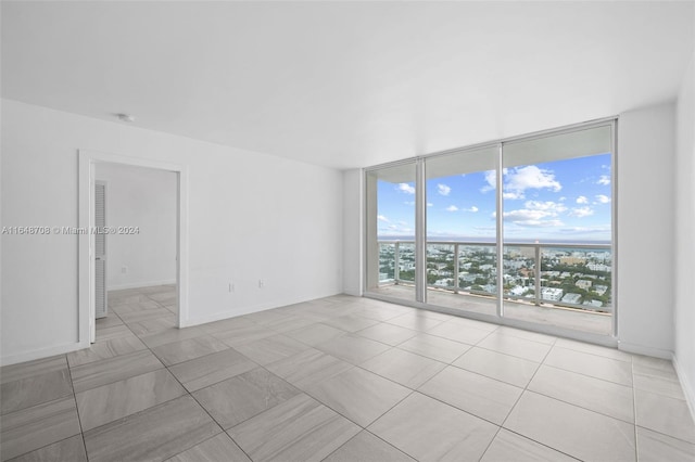 tiled empty room featuring a wall of windows