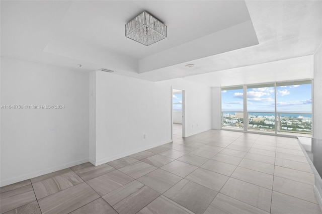 unfurnished room featuring a notable chandelier and a tray ceiling