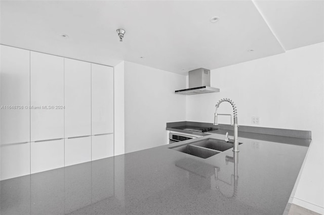 kitchen with white cabinets, wall chimney exhaust hood, and sink