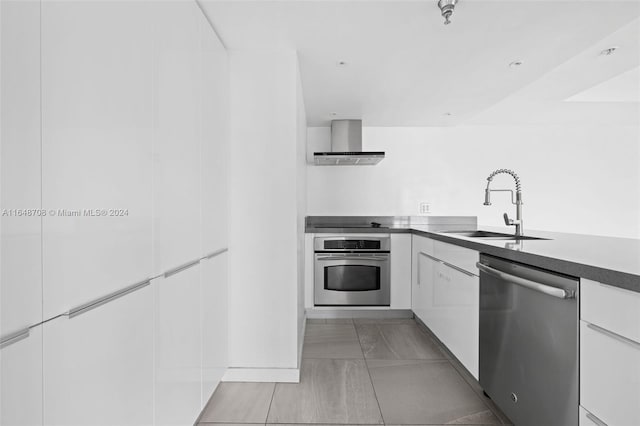 kitchen featuring stainless steel appliances, extractor fan, white cabinets, and sink