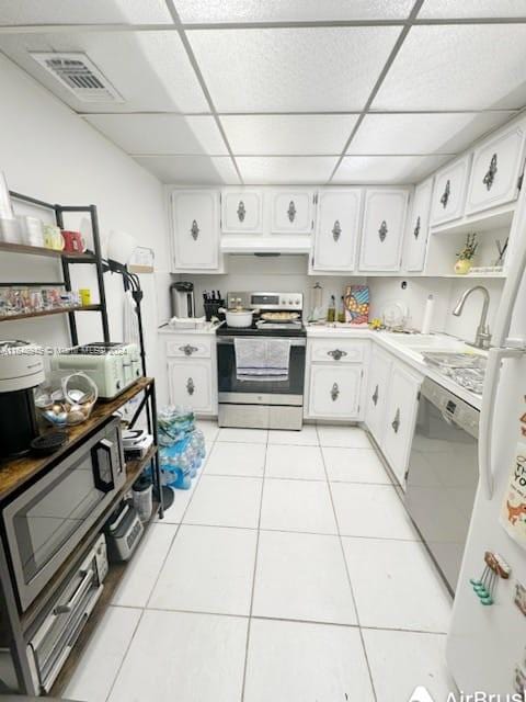 kitchen with light tile patterned floors, appliances with stainless steel finishes, white cabinets, and a drop ceiling