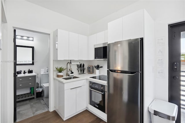 kitchen featuring appliances with stainless steel finishes, dark hardwood / wood-style flooring, sink, and white cabinets