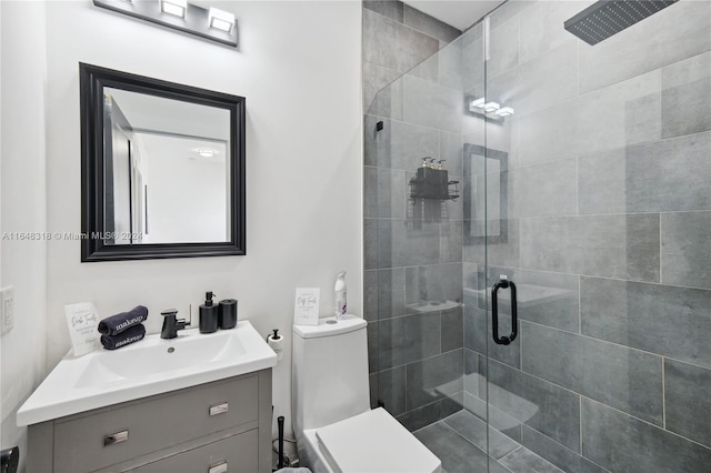 bathroom featuring vanity, a shower with shower door, and toilet