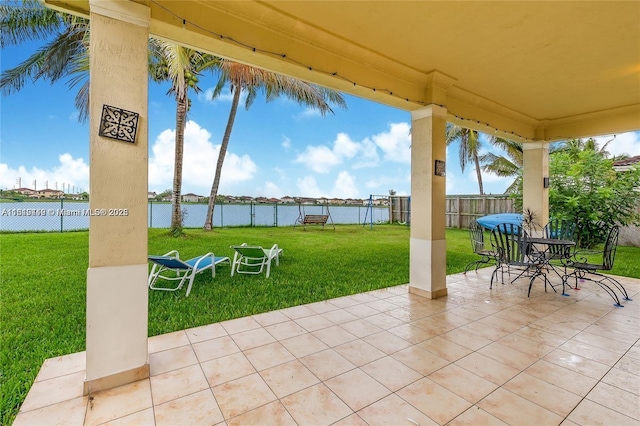 view of patio featuring fence, outdoor dining area, and a water view