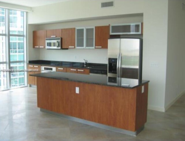 kitchen featuring white oven, stainless steel fridge, a kitchen island, and sink