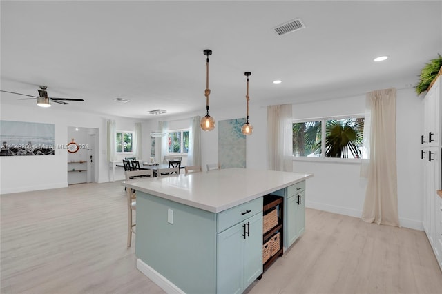 kitchen with light hardwood / wood-style floors, a center island, a breakfast bar, hanging light fixtures, and ceiling fan