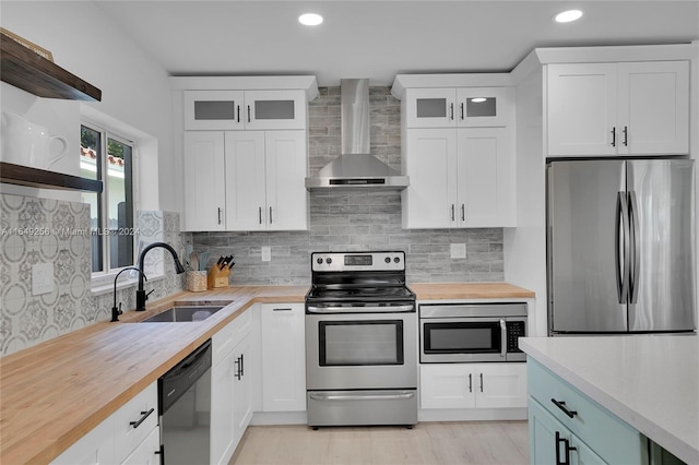 kitchen featuring stainless steel appliances, wall chimney exhaust hood, tasteful backsplash, and sink