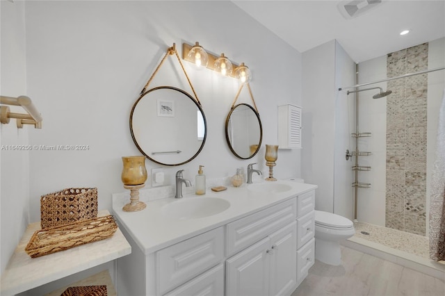 bathroom featuring vanity, toilet, a tile shower, and tile patterned flooring